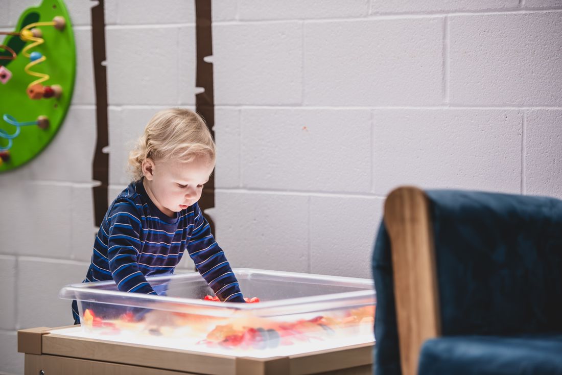 A toddler plays at a glowing light table