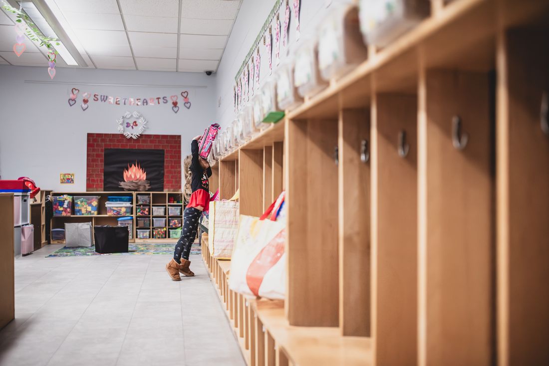 A long row of wooden cubbies in a classroom leading toward a reading nook
